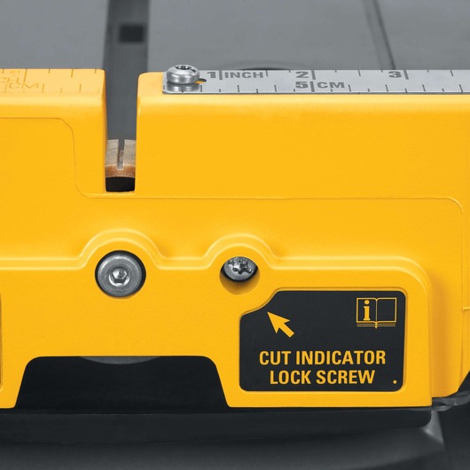 Close-up view of a yellow DEWALT tool showing detailed measurement markings in inches and centimeters, as well as a label indicating 'CUT INDICATOR LOCK SCREW.'