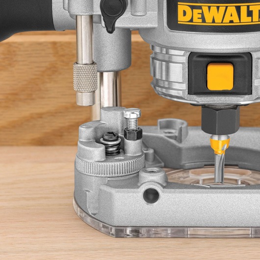 Close-up view of a DEWALT wood router tool in operation, showing the router bit cutting into a wooden surface.
