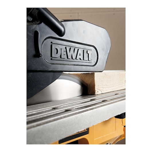 Close-up image of a DEWALT branded power saw cutting through a piece of wood.