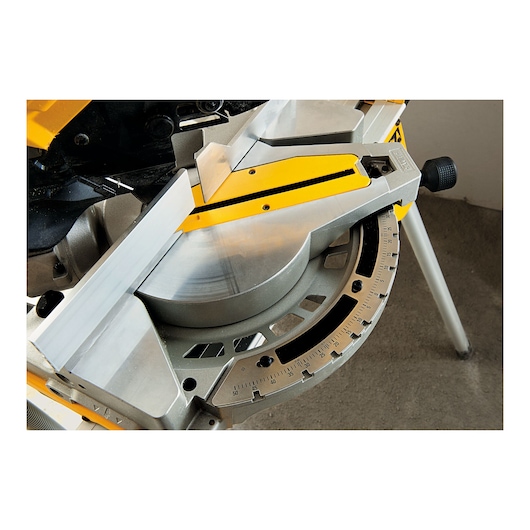 Close-up view of a DEWALT miter saw, showing the angle adjustment mechanism and measurement scale.