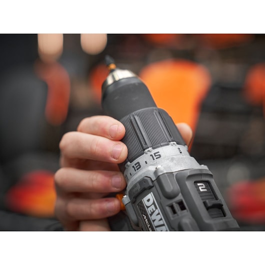 Close-up of a hand adjusting the settings on a DEWALT cordless power drill with visible control numbers and part of the DEWALT logo.