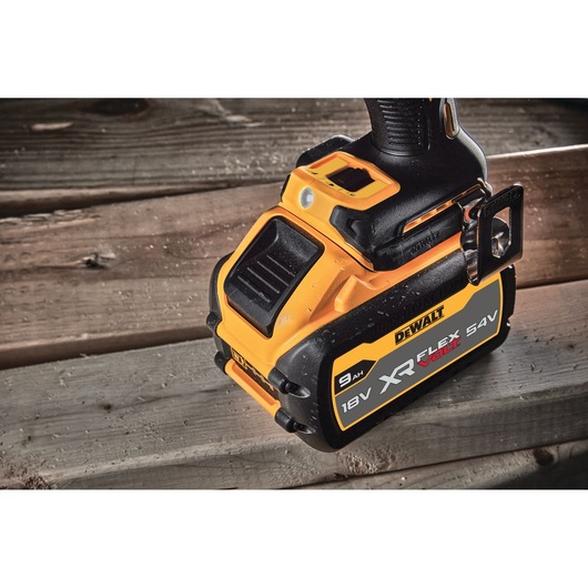 Close-up of a DEWALT cordless power tool showing the XR FLEXVOLT 18V/54V 9Ah battery attached, placed on a wooden surface.