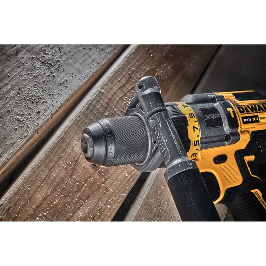 Close-up image of a DEWALT 18V XR cordless drill model DCD999X1, featuring its handle and chuck, placed on wooden planks with wood shavings visible.