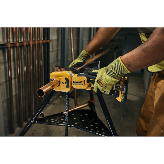 DEWALT pipe tool in use. Photography category. SKUs: DCE154N, DCE154N-XJ. Worker wears gloves.