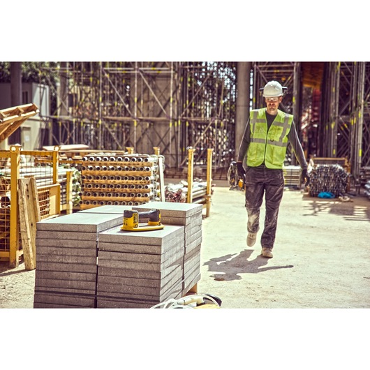 Construction worker walks towards a column of concrete blocks on which sits a Grabo 18V XR Suction Lifter