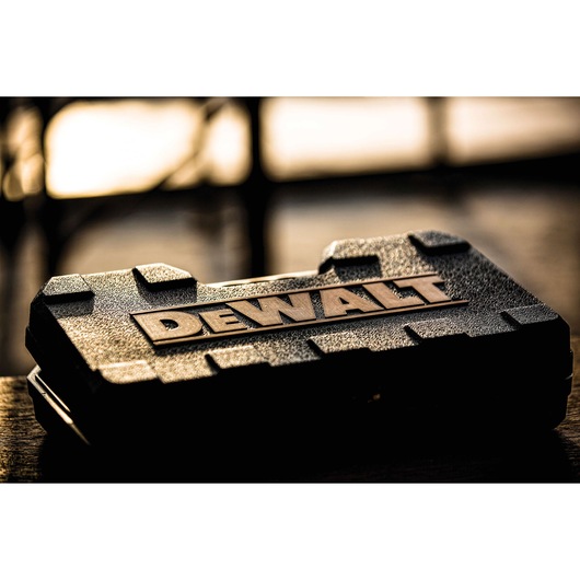 A close-up of a textured DEWALT hard plastic tool case with the DEWALT logo prominently displayed on top, set against a blurred background.