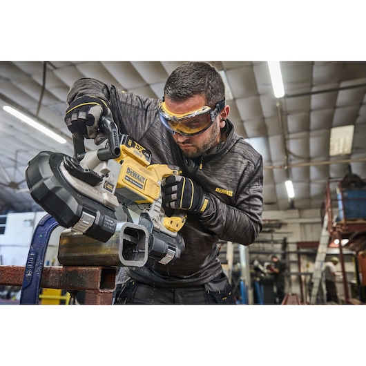 DEWALT DCS374N, DCS374N-XJ band saw in use on metal pipe in workshop. Photography category.