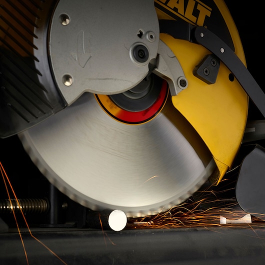 Close-up of a DEWALT circular saw cutting through a metal rod, with sparks flying from the contact point.