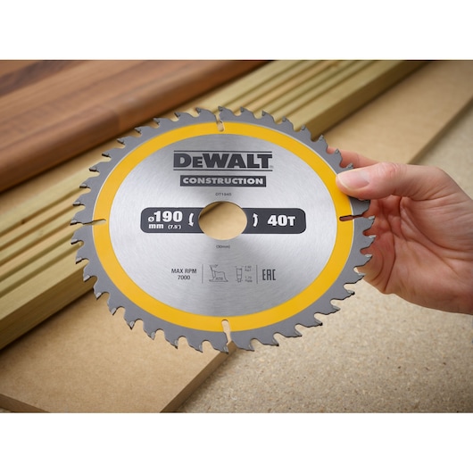 Hand holding a DEWALT DT1945 circular saw blade with 190mm diameter and 40 teeth for construction use.