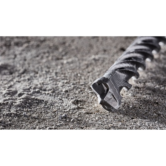 Close-up of a DEWALT DT8914 masonry drill bit lying on a rough concrete surface.