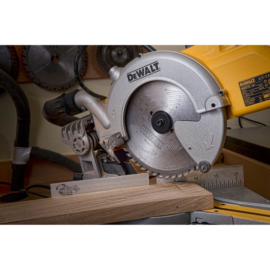 DEWALT DWS778 mitre saw cutting wood, close-up view in a workshop setting.