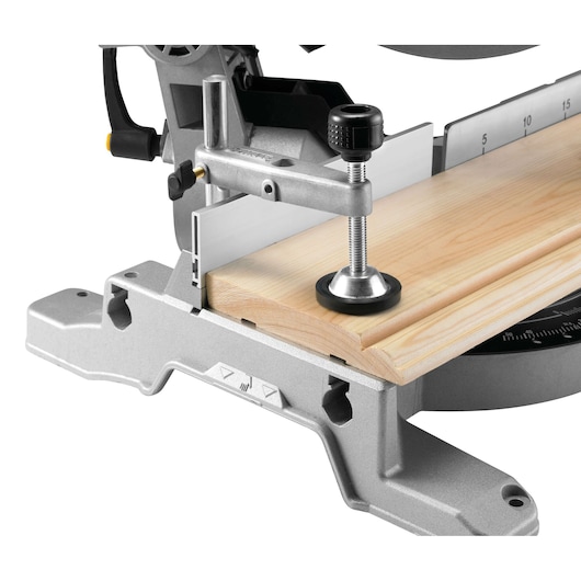 Close up of a mitre saw clamping a wooden board, showing precise cutting and measurement guide.