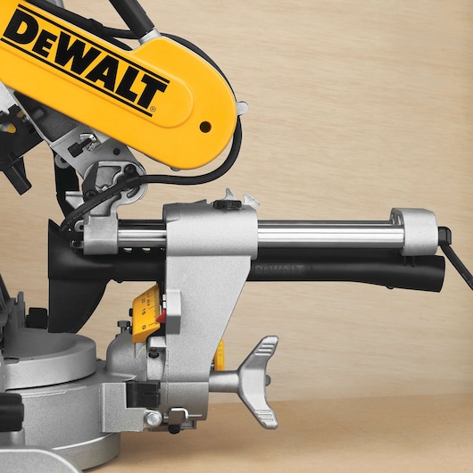 Close-up view of a DEWALT DWS780 sliding compound miter saw, highlighting the yellow and silver components and adjustment features.