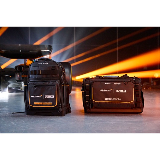 DEWALT McLaren special edition backpack and tool bag with black and orange design on a studio floor.