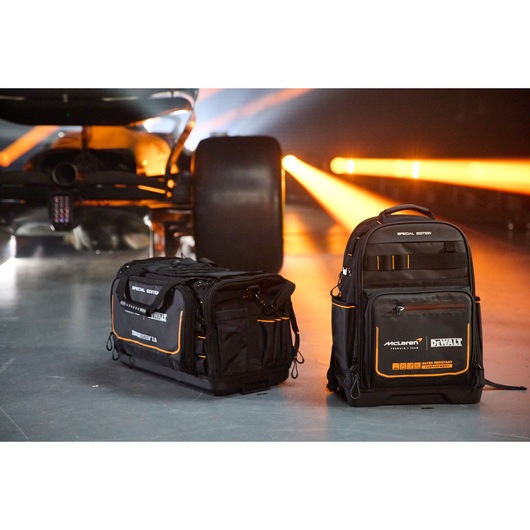 DEWALT black tool bag and backpack special edition placed beside a race car with orange lights in the background.
